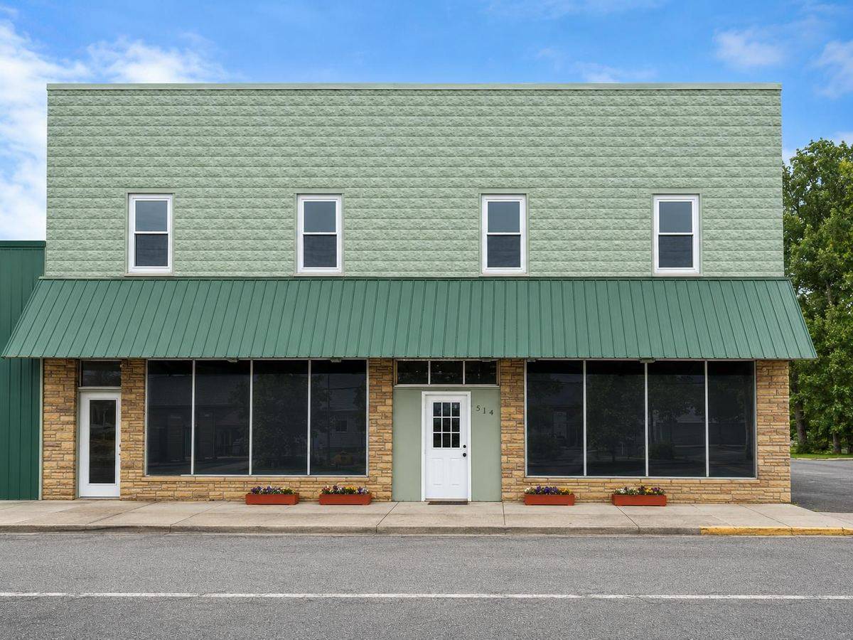 Front exterior of Meadow River Lofts, a two-story green building with a standing-seam metal awning and street-level storefronts on Nicholas Street